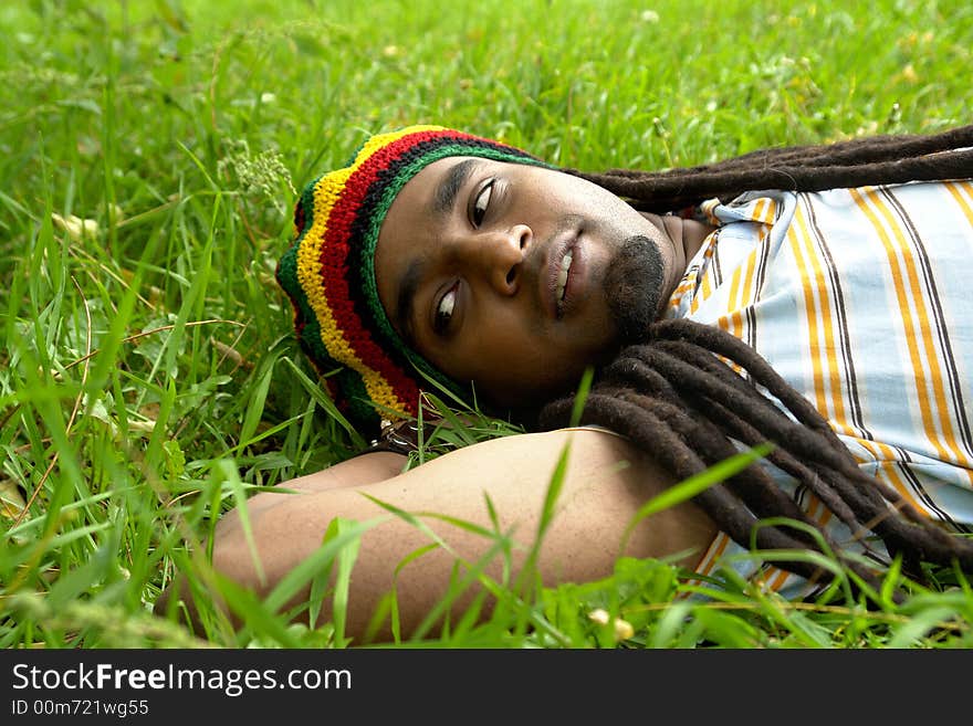 Sad Rastafarian Jamaican thinking laid on grass. Sad Rastafarian Jamaican thinking laid on grass