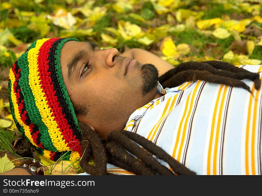 Sad Rastafarian Jamaican thinking laid on grass. Sad Rastafarian Jamaican thinking laid on grass