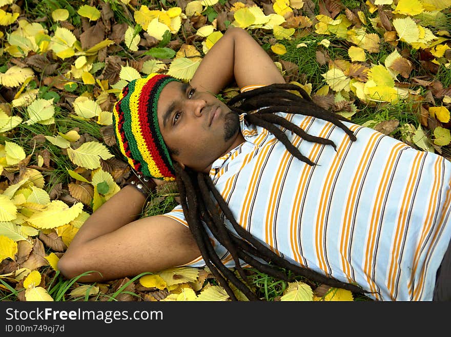 Sad Rastafarian Jamaican thinking laid on grass. Sad Rastafarian Jamaican thinking laid on grass