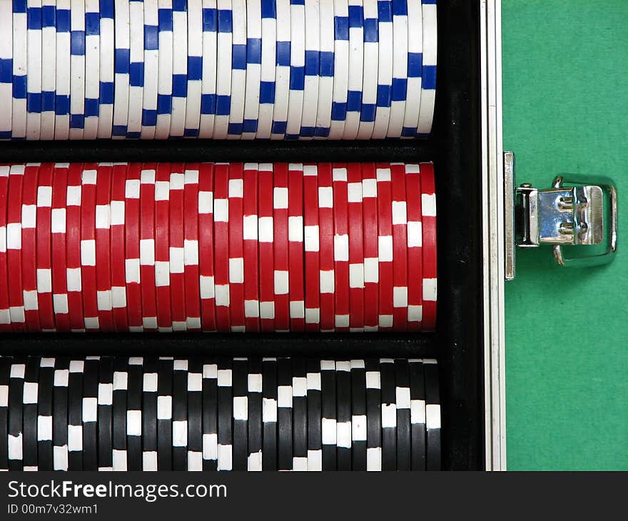 A close up on poker chips arranged inside a carrying case. Three rows with white, red and black chips.