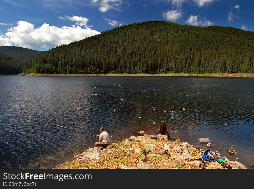 Two men fishing in a polluted lake in Romania. Full of PET s, papers, oils and so on . Two men fishing in a polluted lake in Romania. Full of PET s, papers, oils and so on ...