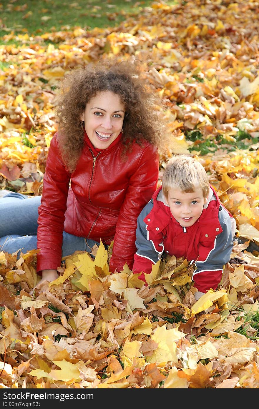 Mother and child sit among fallen leaves. Mother and child sit among fallen leaves