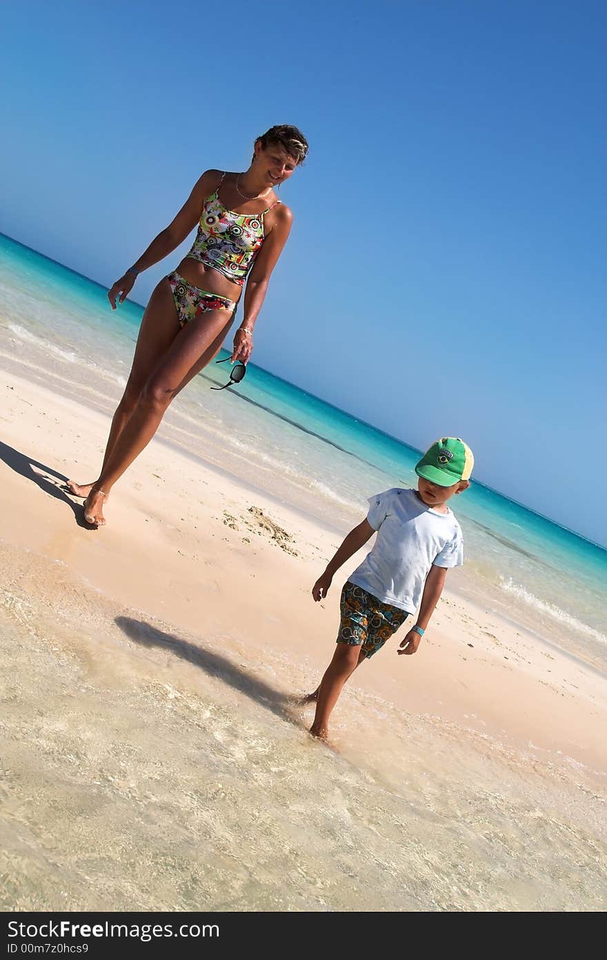 Mum and the son walk on a coast of the tropical sea