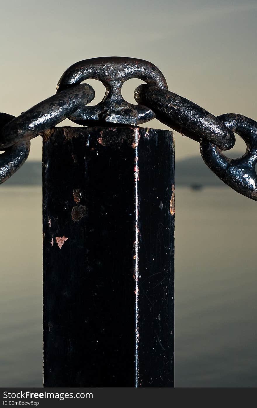 A solid black chain with a placid lake in background. A solid black chain with a placid lake in background