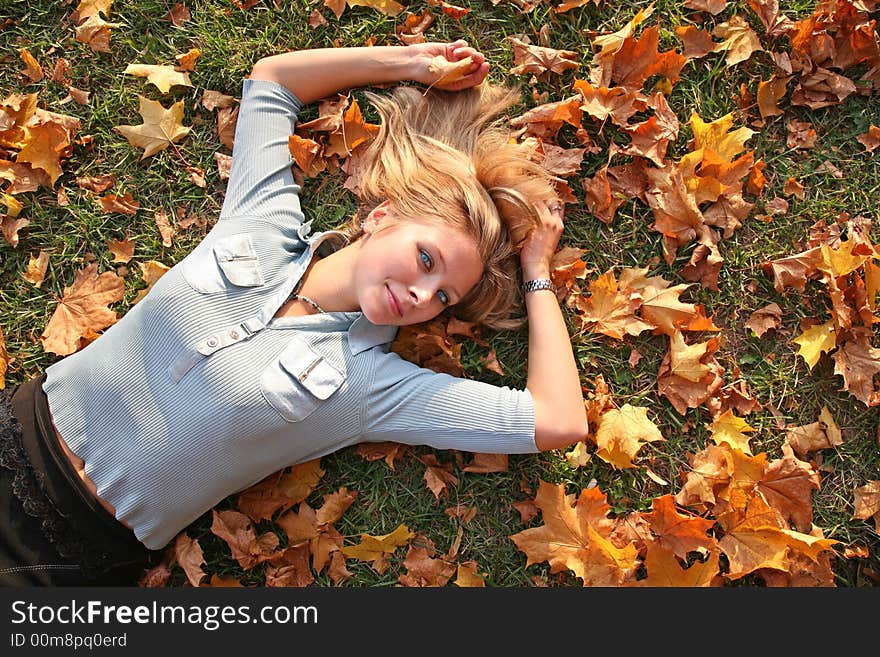 Blue-eyed blond lies among yellow leaves. Blue-eyed blond lies among yellow leaves