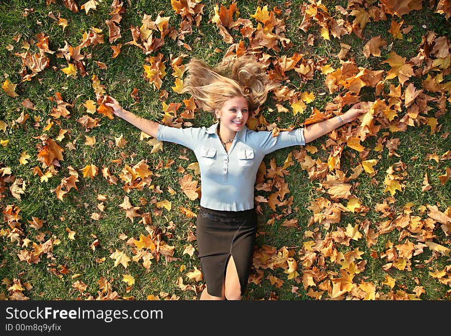 Blue-eyed blond lies among yellow leaves. Blue-eyed blond lies among yellow leaves