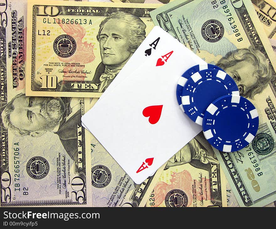 A pair of ace cards and three blue poker chips  over a background formed by bills of us dollars. A pair of ace cards and three blue poker chips  over a background formed by bills of us dollars