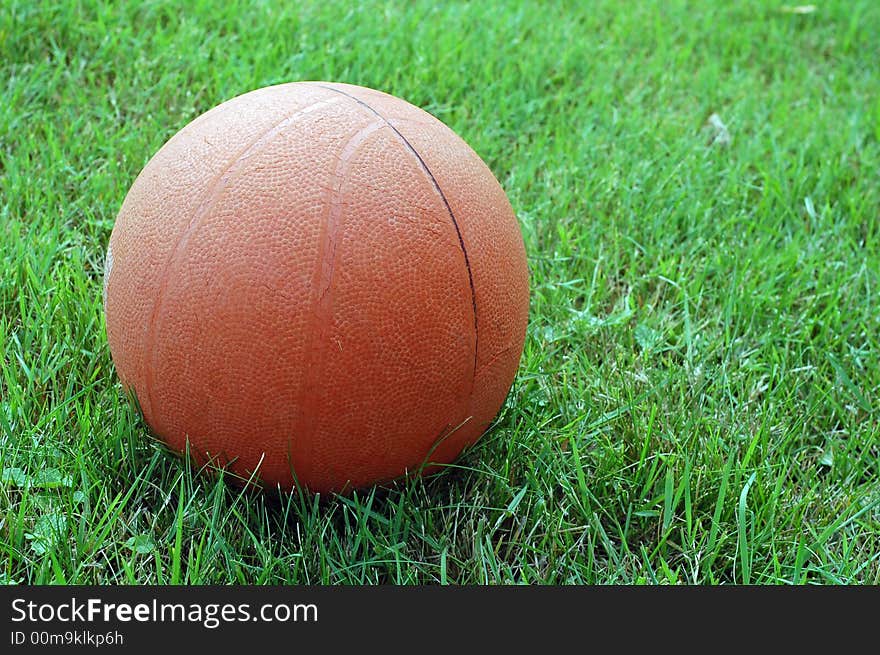 Photo of solitary basket ball sitting on grass outdoors. Photo of solitary basket ball sitting on grass outdoors.