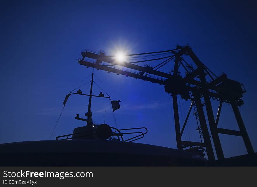 Shapes of cranes at a cargo harbor in backlight. Shapes of cranes at a cargo harbor in backlight