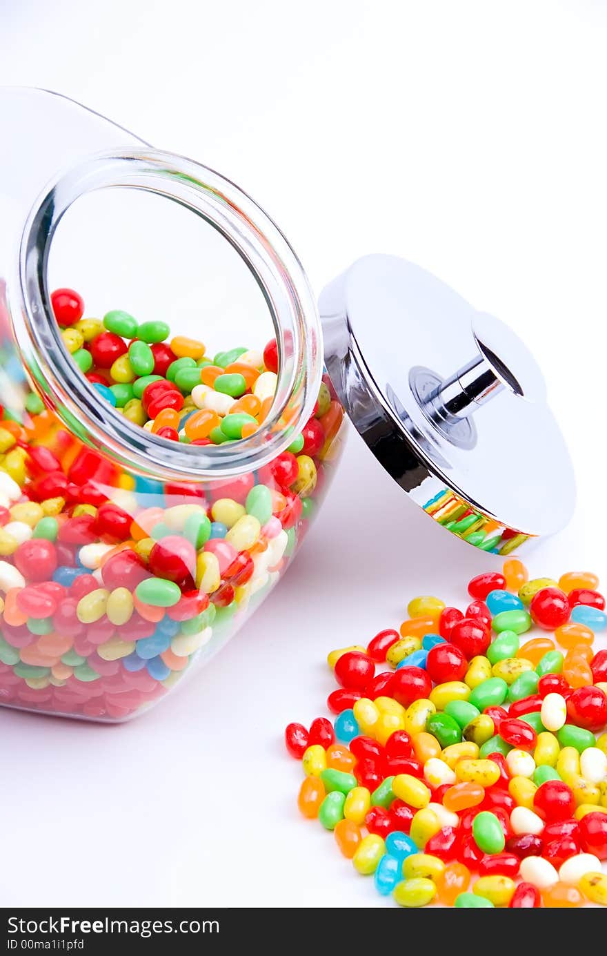 Vertical cropped view of clear open jar and pile of jelly beans. Vertical cropped view of clear open jar and pile of jelly beans