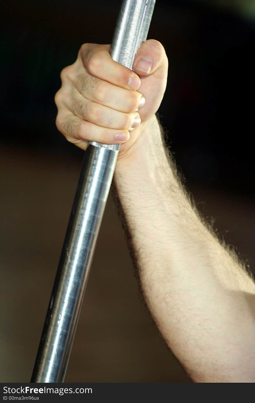 One hand held close a Yoke in Vertical Position / Exercises in the gym / Blur Dark Background. One hand held close a Yoke in Vertical Position / Exercises in the gym / Blur Dark Background