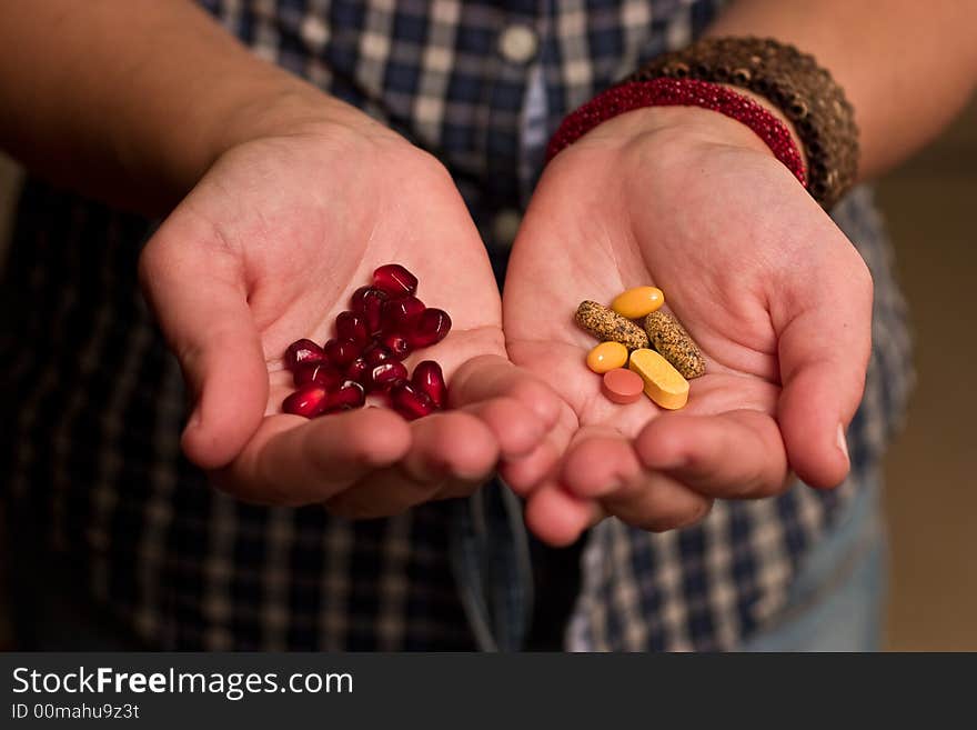 Hands holding pills and pomegranate seeds