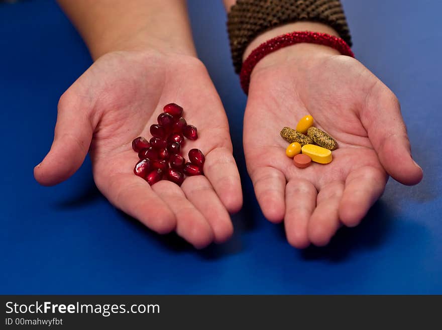 Hands holding pills and pomegranate seeds