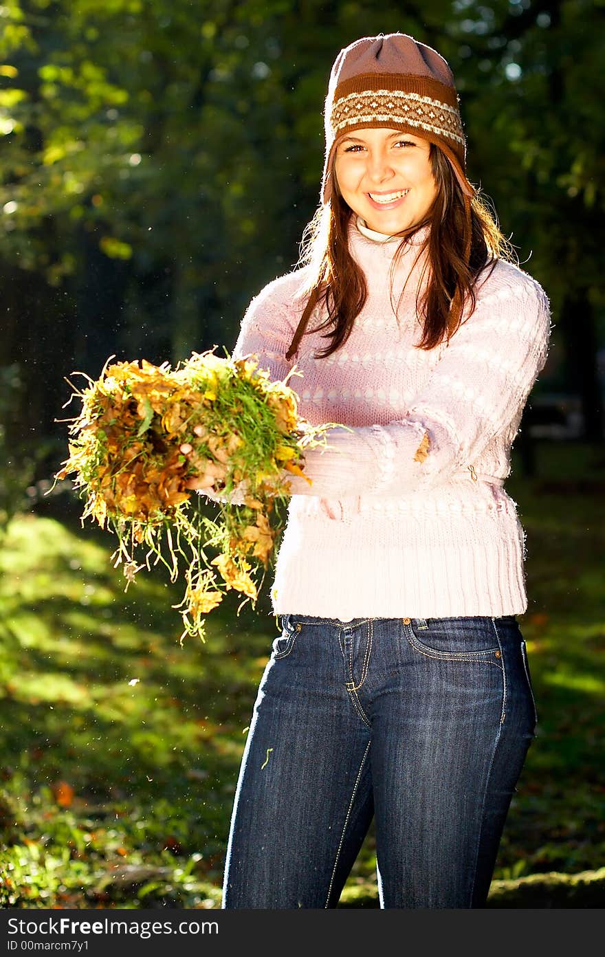 Beautiful young girl holding leaves and grass in her hands. Beautiful young girl holding leaves and grass in her hands