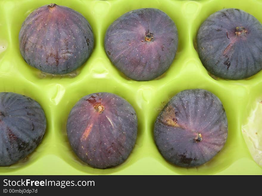 Ripe fresh figs in green packaging background