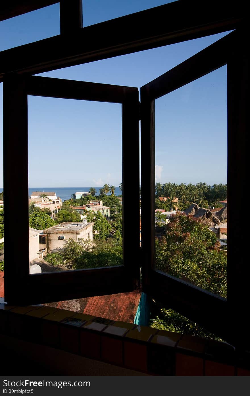 A window opens out onto a view of a tropical fishing village. A window opens out onto a view of a tropical fishing village.