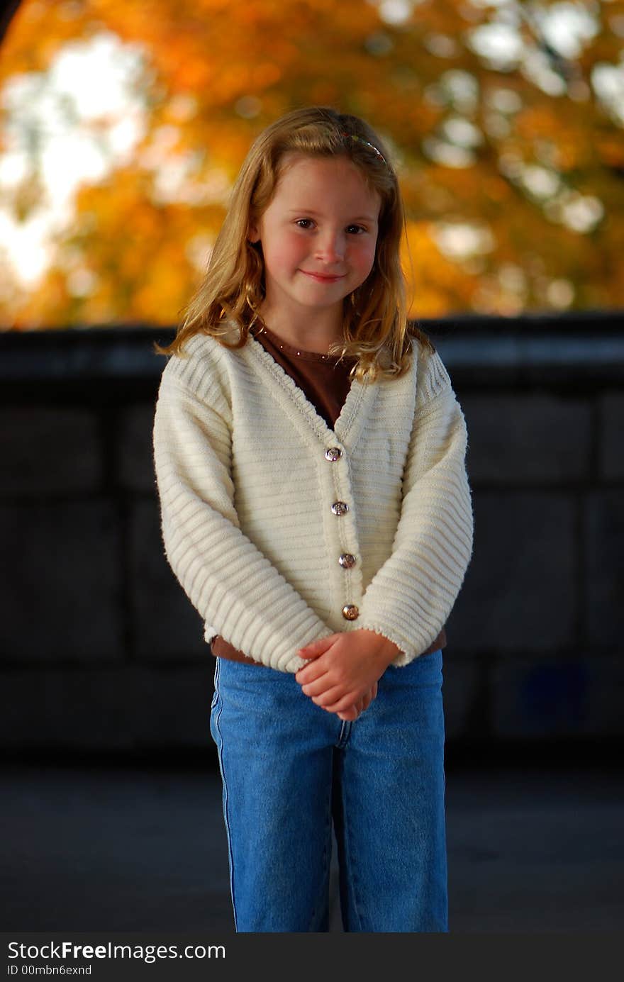 A pretty little girl with a sweet smile poses for an outdoor portrait. A pretty little girl with a sweet smile poses for an outdoor portrait.