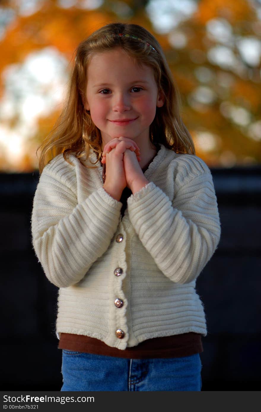 A pretty little girl with a sweet smile poses for an outdoor portrait. A pretty little girl with a sweet smile poses for an outdoor portrait.