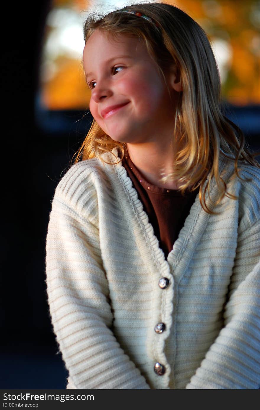 A pretty little girl with a sweet smile poses for an outdoor portrait. A pretty little girl with a sweet smile poses for an outdoor portrait.