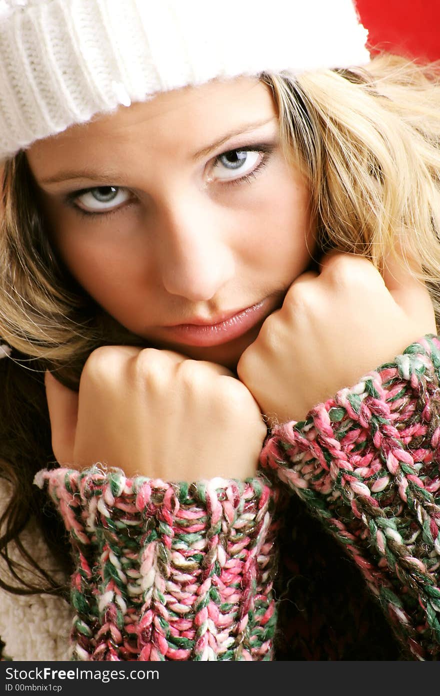 Winter portrait of a beautiful young woman is freezing with a cap and a scarf. Winter portrait of a beautiful young woman is freezing with a cap and a scarf