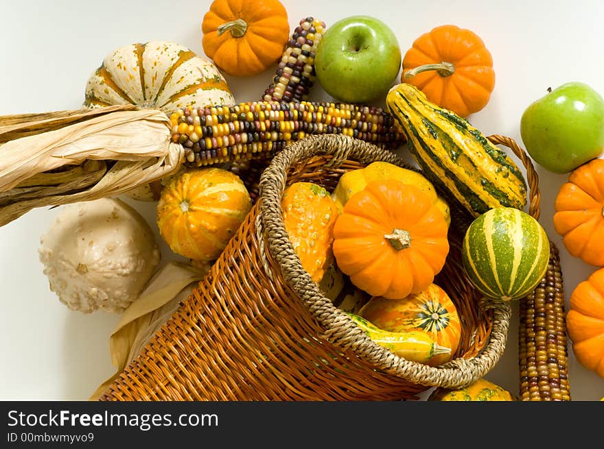 Cornucopia with fall harvest items including pumpkins, gords, apples and indian corn