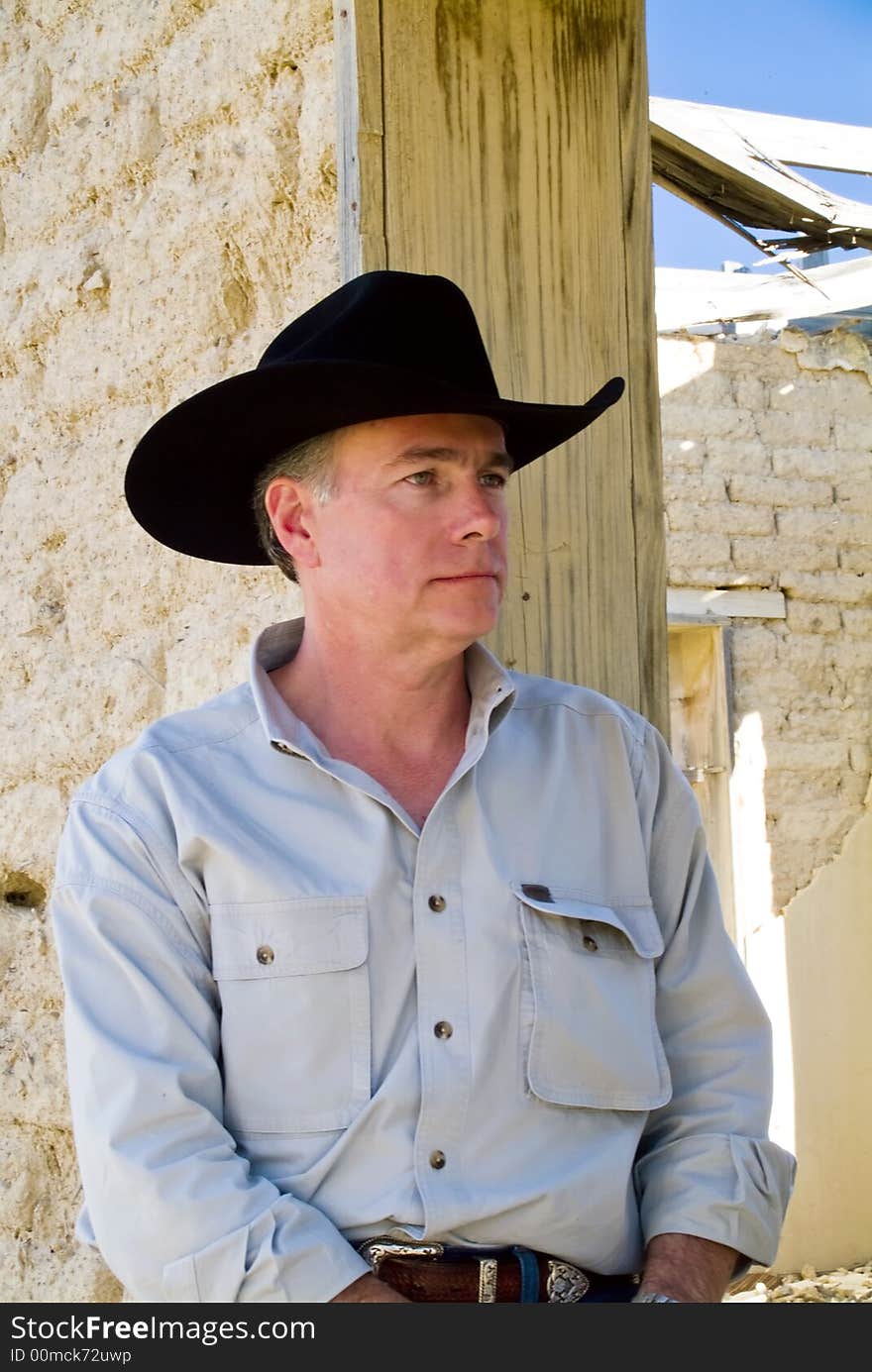 A man leaning against the wall of an abandoned adobe brick structure. A man leaning against the wall of an abandoned adobe brick structure.