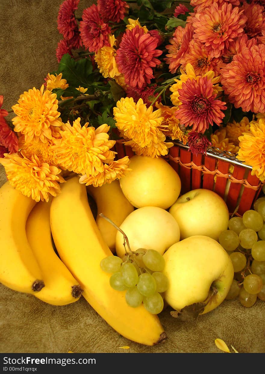 Harvest still-life: fruits on basket and flowers