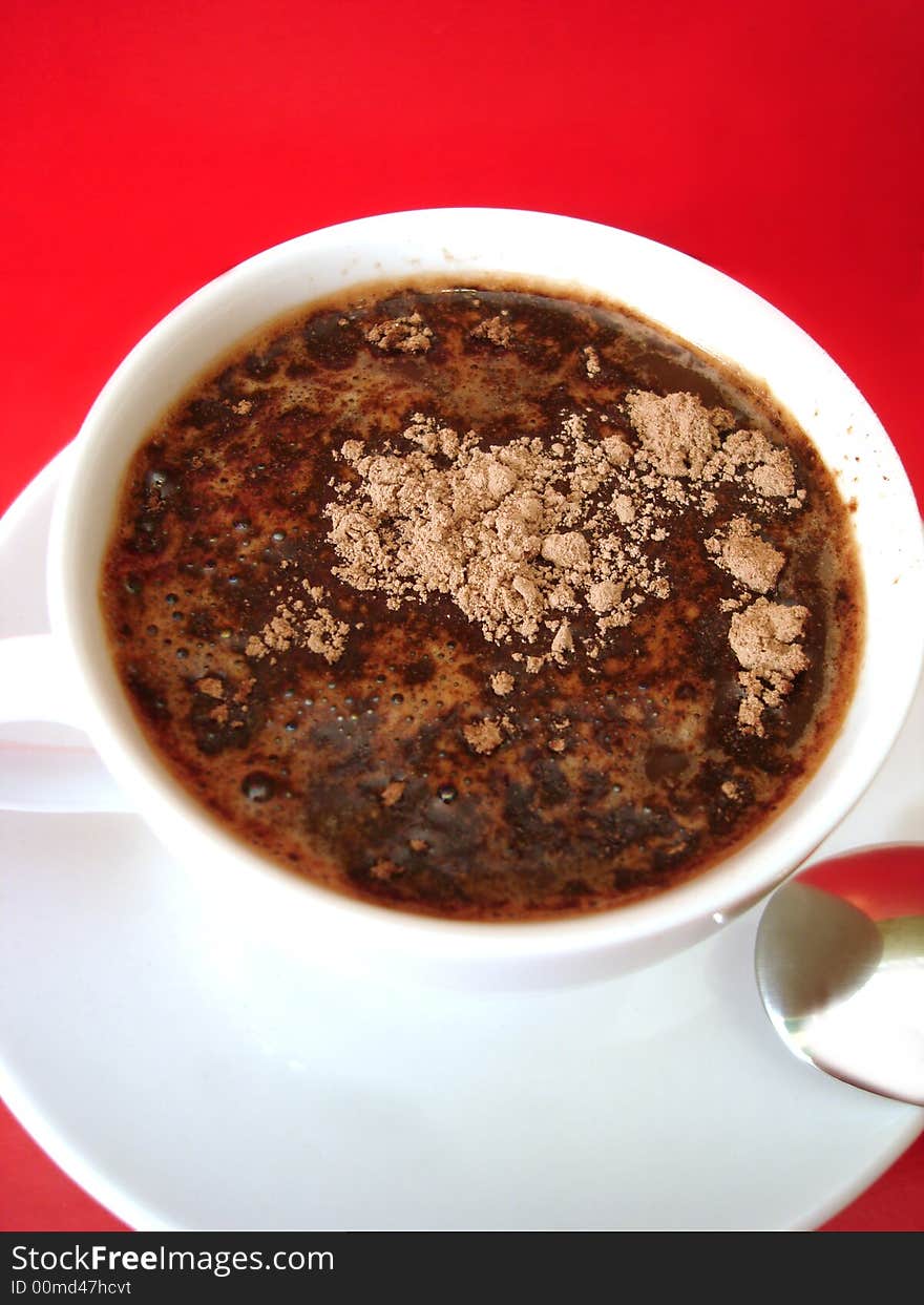 White cup of coffee with spoon on red background