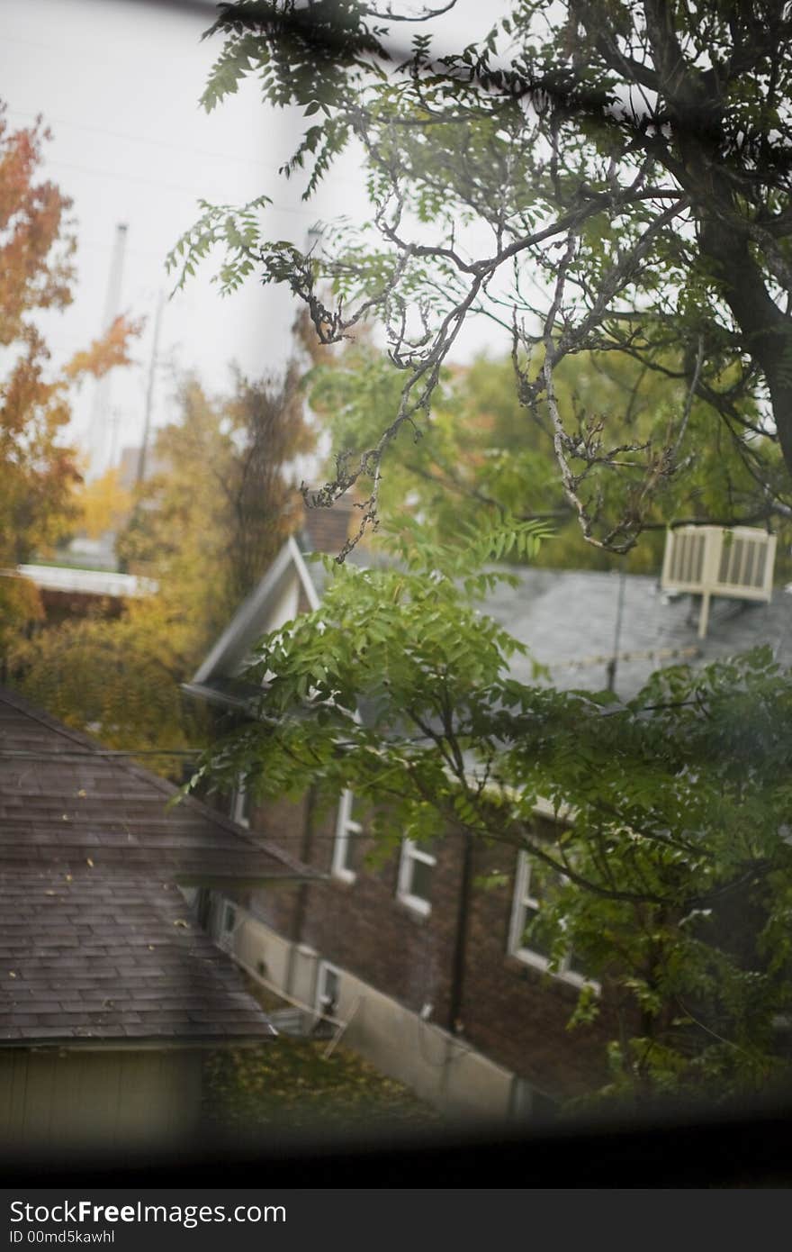 Through the panes of a window, two houses made of brick located side by side in autumn surroundings. Through the panes of a window, two houses made of brick located side by side in autumn surroundings