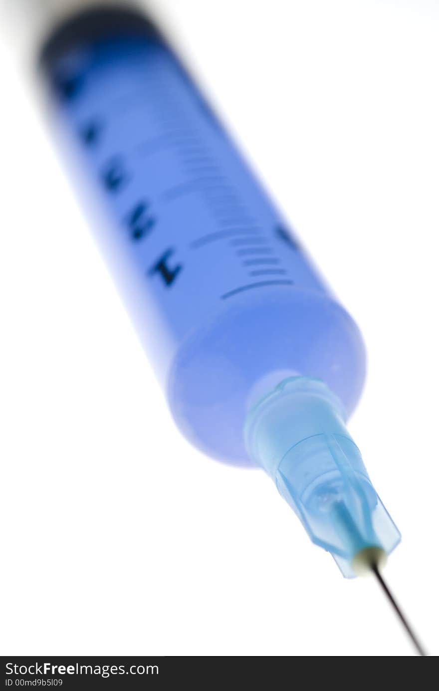 Close-up on white background of a syringe with needle and blue liquide inside. Close-up on white background of a syringe with needle and blue liquide inside.