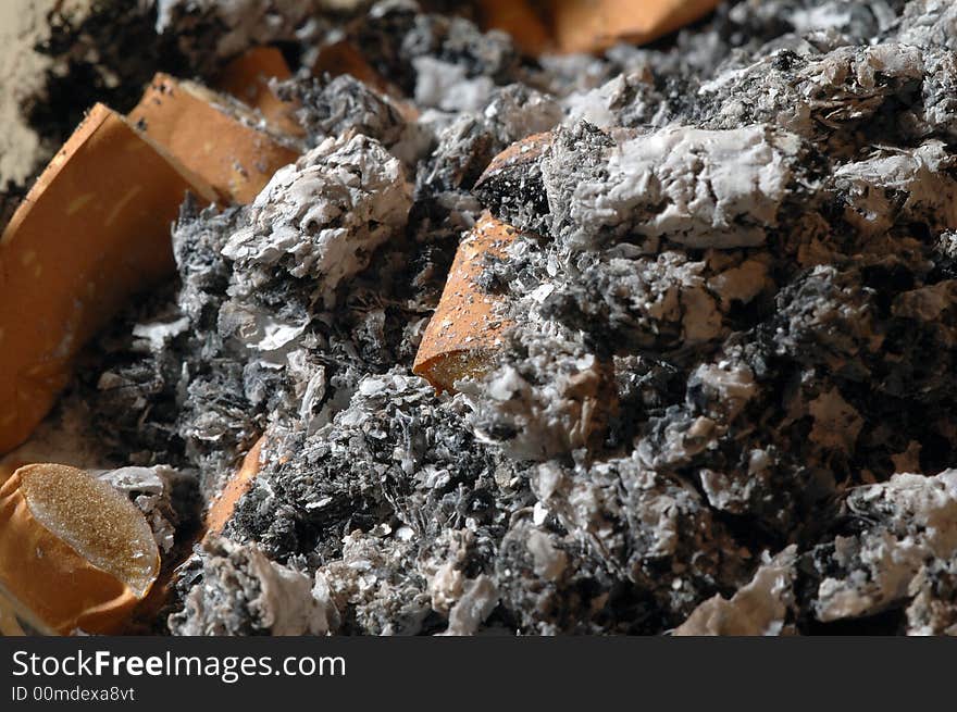 Cigarette butts and ashes in a glass ashtray, closeup. Cigarette butts and ashes in a glass ashtray, closeup