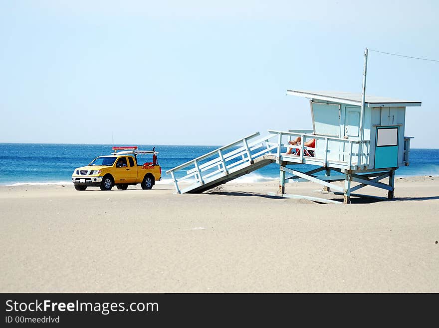 Lifeguard driving truck past lifeguard sitting on lifeguard stand. Lifeguard driving truck past lifeguard sitting on lifeguard stand