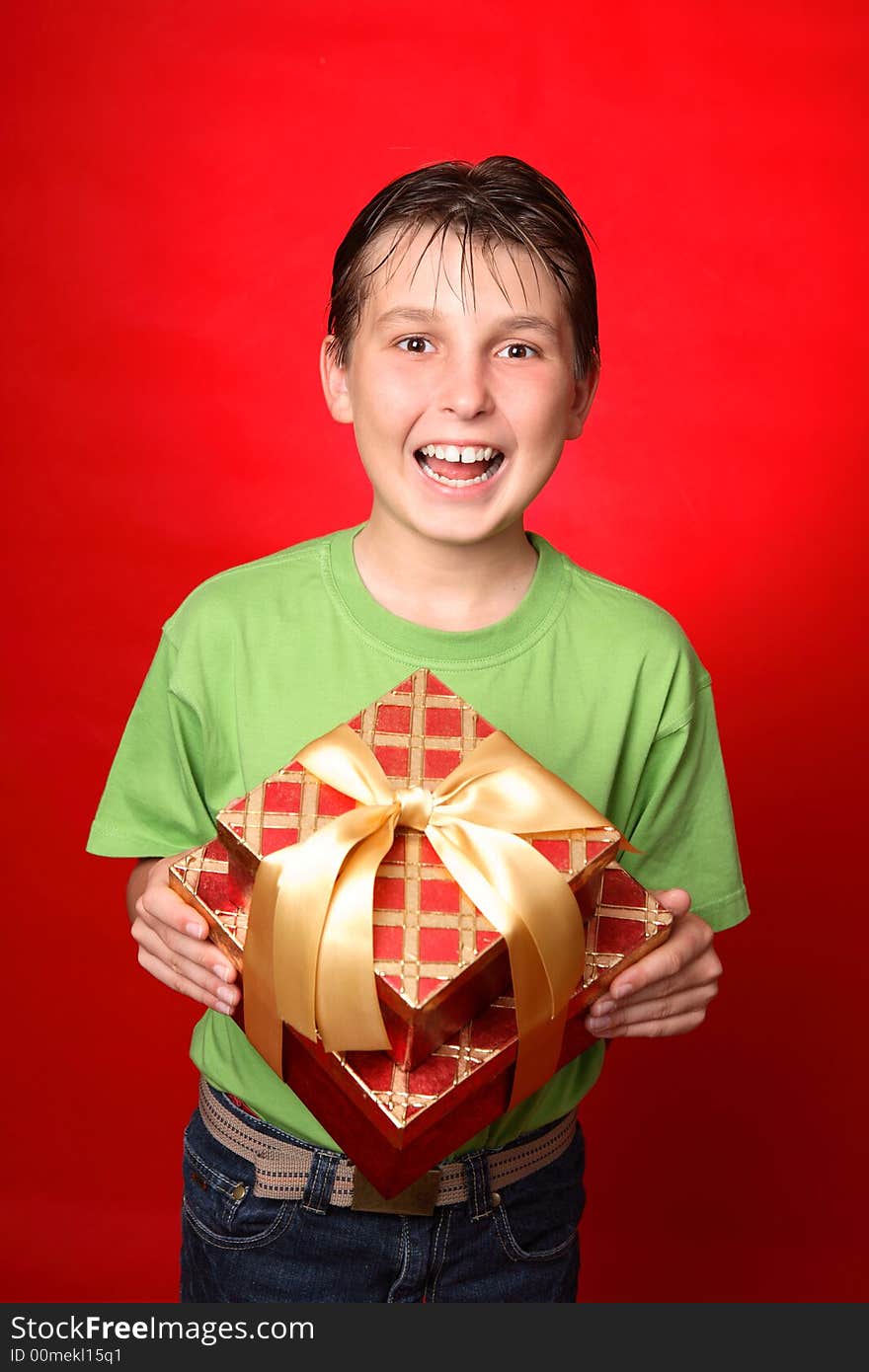 Jovial child holding a red and gold gift tied with gold ribbon. Jovial child holding a red and gold gift tied with gold ribbon.