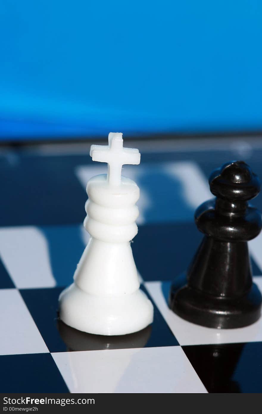 White chess king stands on a chess board with figures