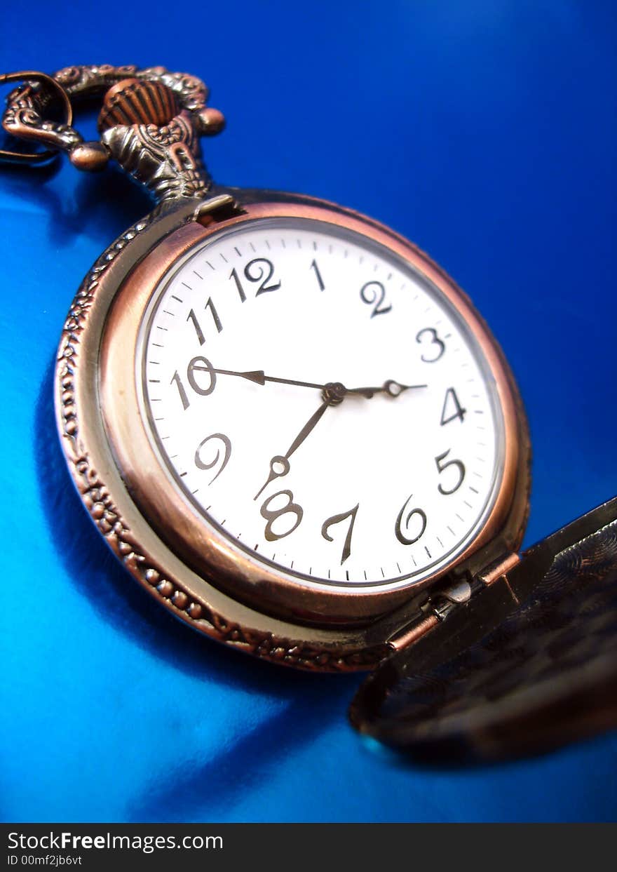 Close-up of old golden clock on blue background