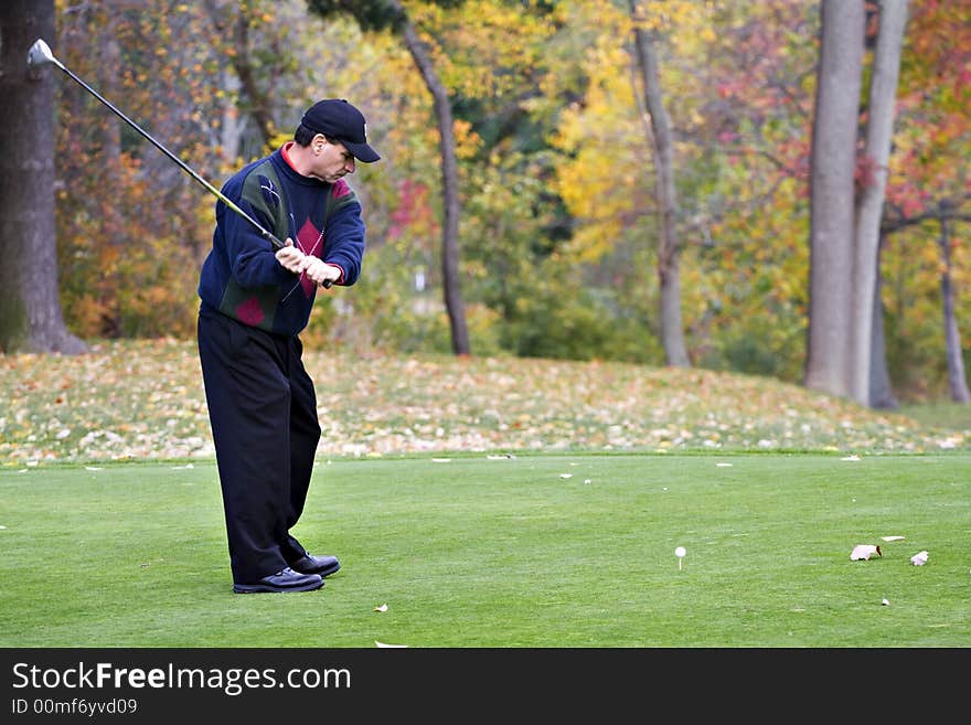 A male golfer plays a game on a beautiful fall day. A male golfer plays a game on a beautiful fall day.