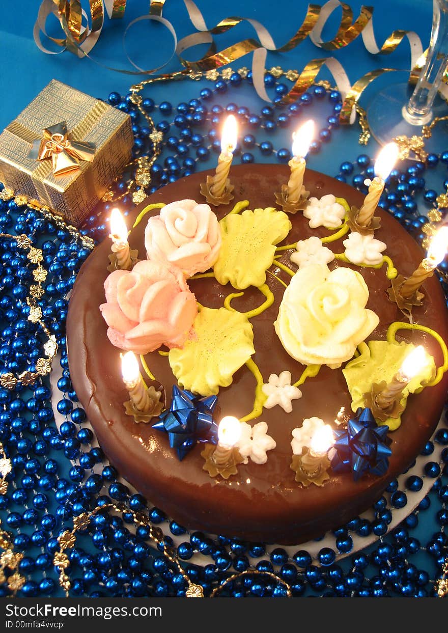 Celebratory table (cake and candles, two glasses with champagne, gift boxes) on blue