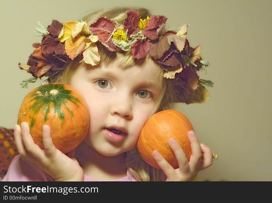 Little girl in diadem from autumn leaves with two little pumpkins in hands. Little girl in diadem from autumn leaves with two little pumpkins in hands