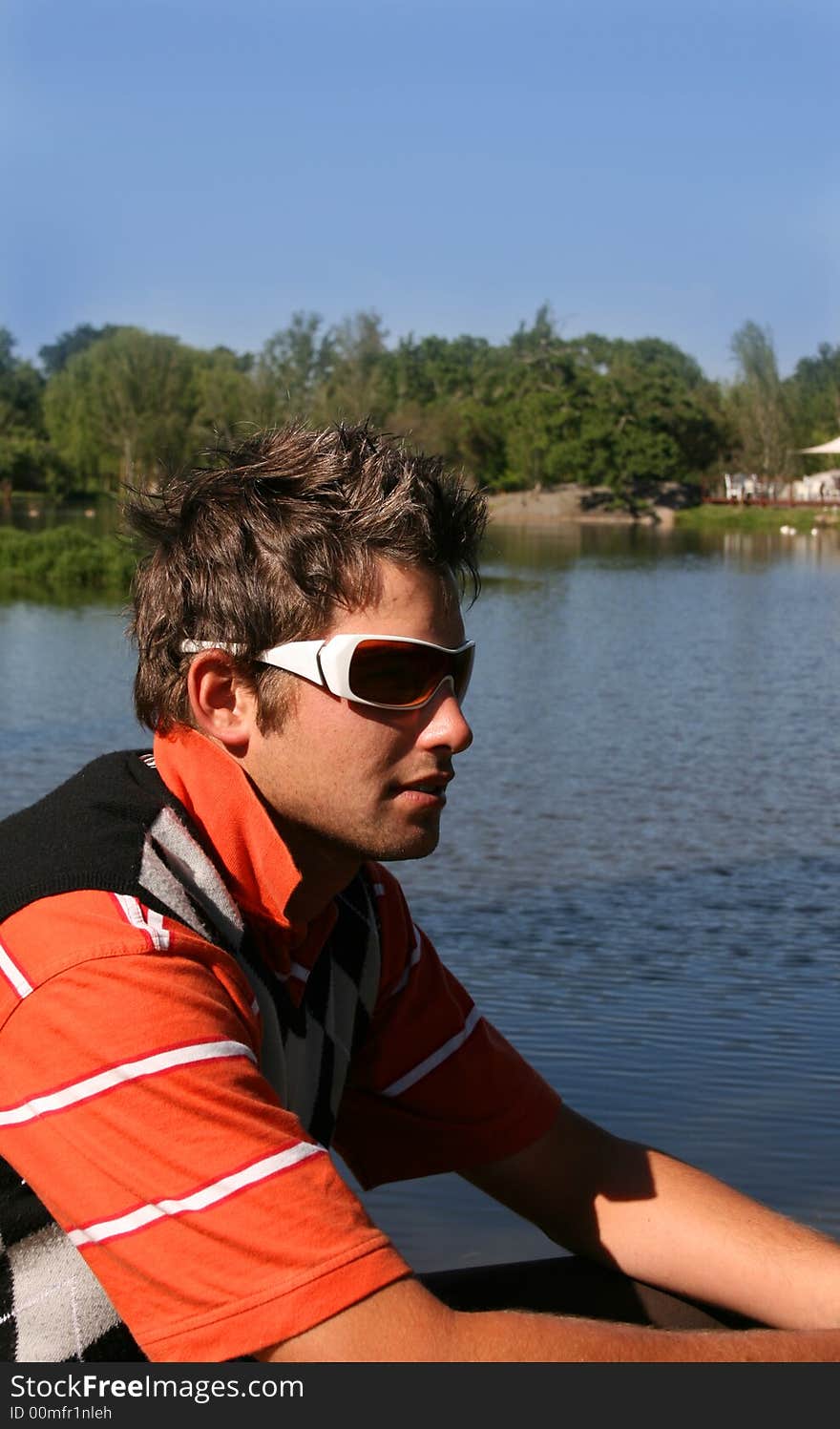 Young man sitting near the edge of a lake. Young man sitting near the edge of a lake