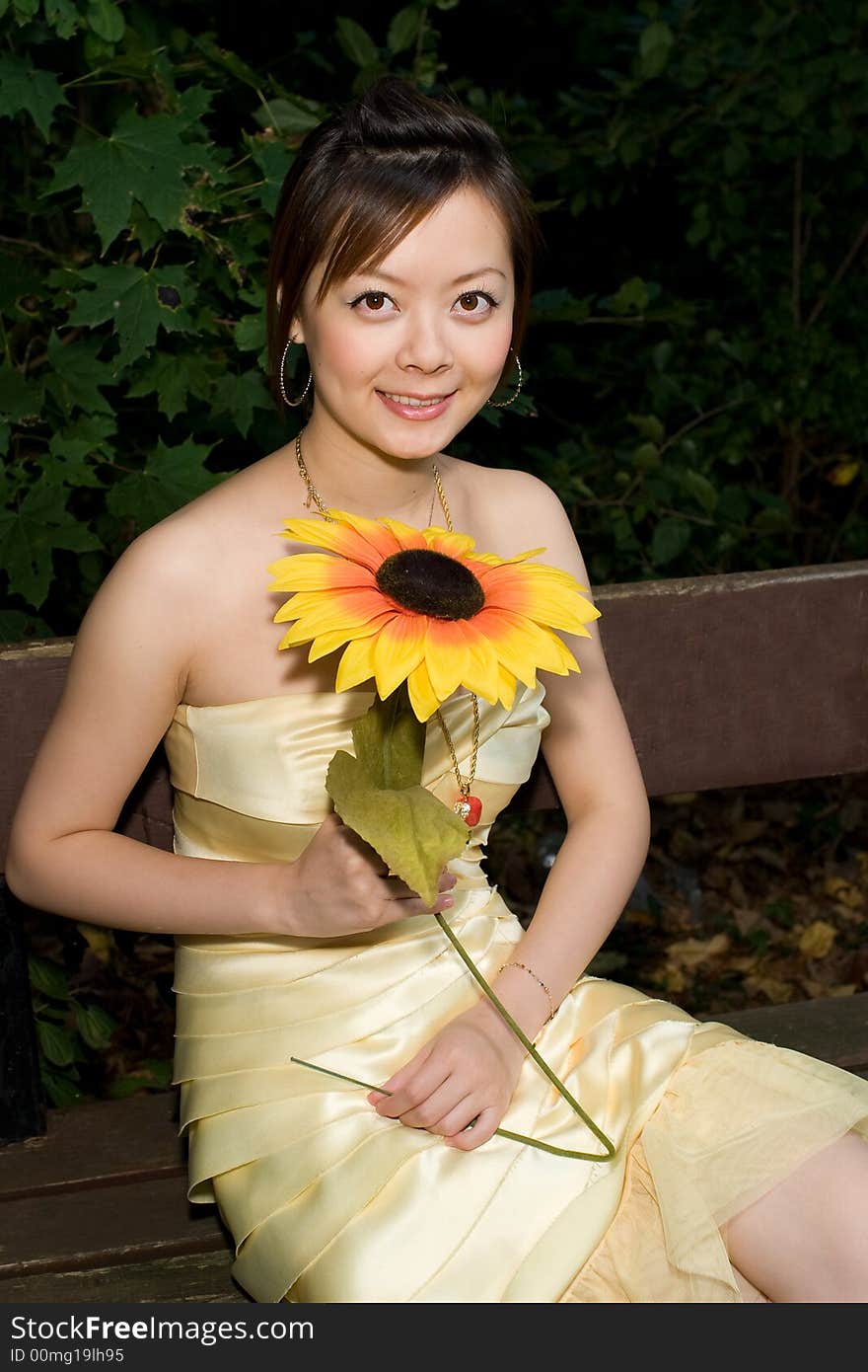 A girl holding a sunflower sitting in chair. A girl holding a sunflower sitting in chair