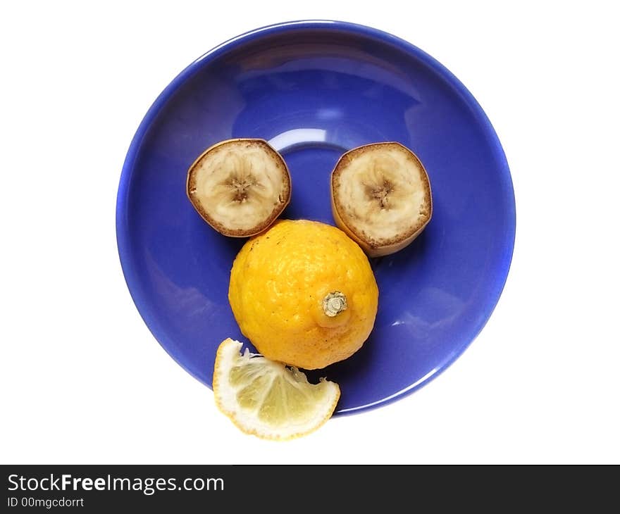 Funny face made of lemon and banana on a blue plate. Funny face made of lemon and banana on a blue plate