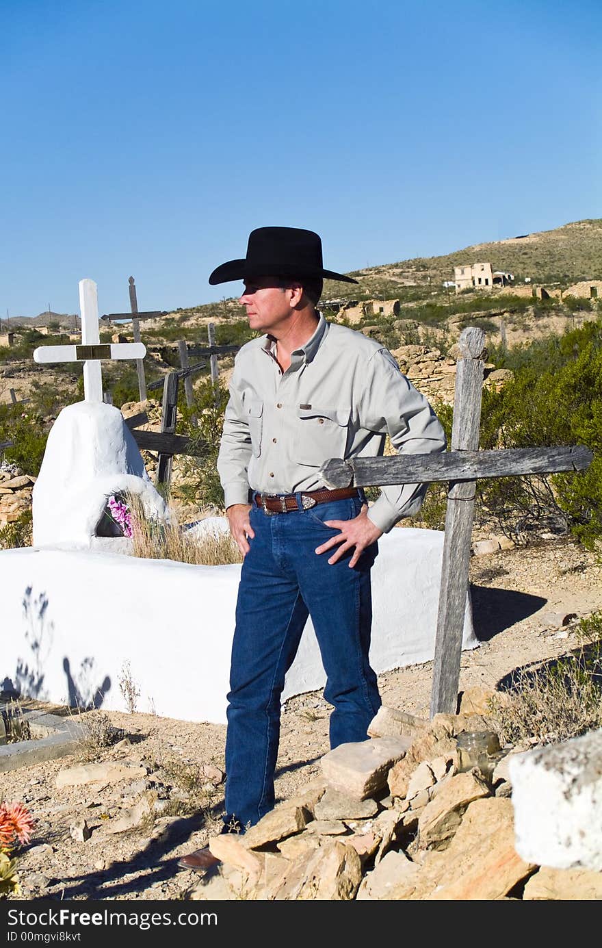 A man dressed in western attire standing in the middle of an old graveyard. A man dressed in western attire standing in the middle of an old graveyard.