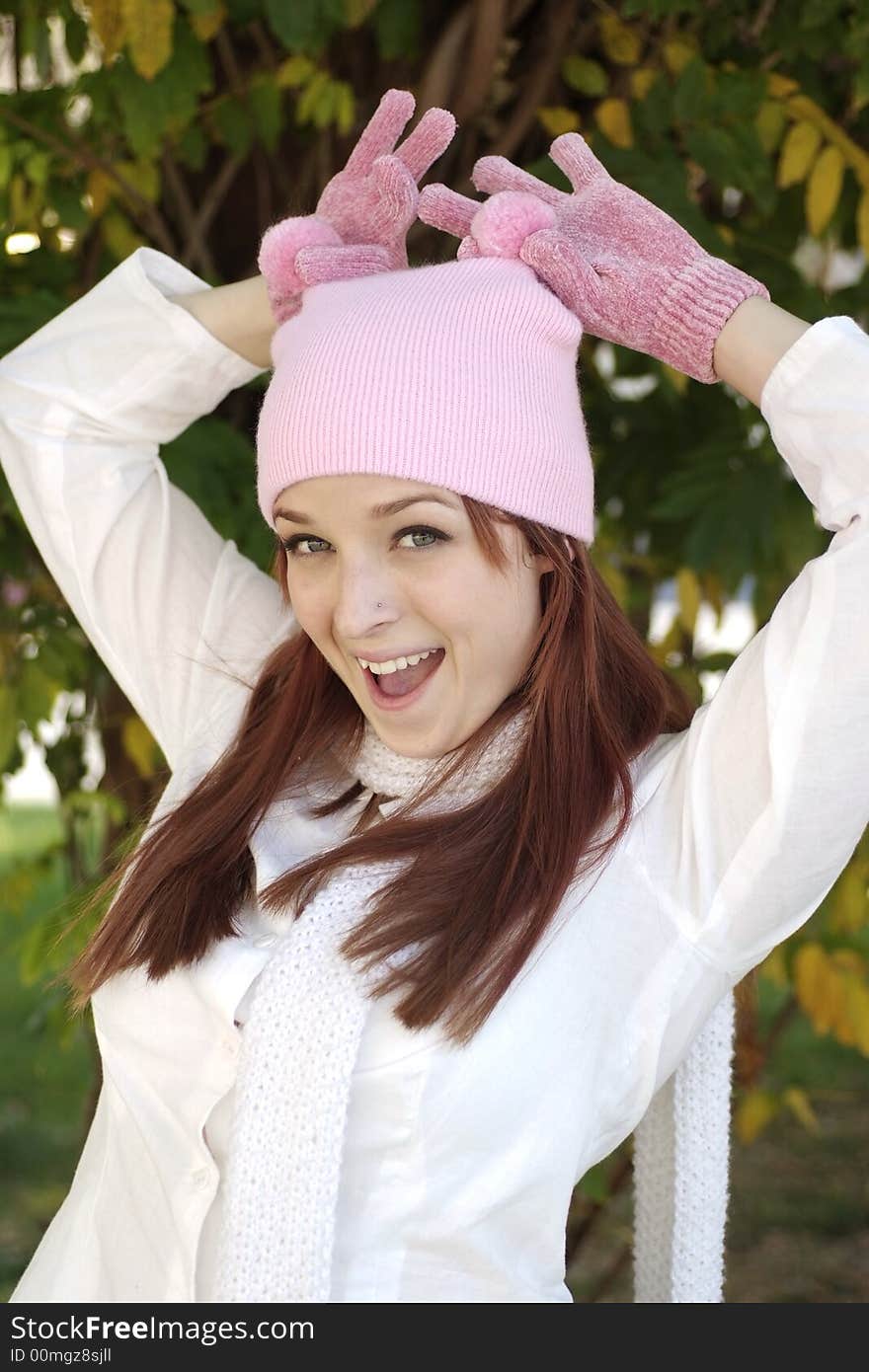 A beautiful woman with a red hair, white scarf, and pink bonnet and gloves. A beautiful woman with a red hair, white scarf, and pink bonnet and gloves.