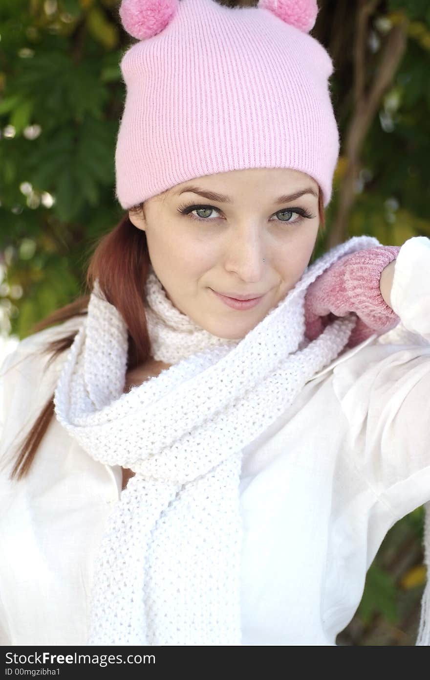 A beautiful woman with a red hair, white scarf, and pink bonnet and gloves. A beautiful woman with a red hair, white scarf, and pink bonnet and gloves.