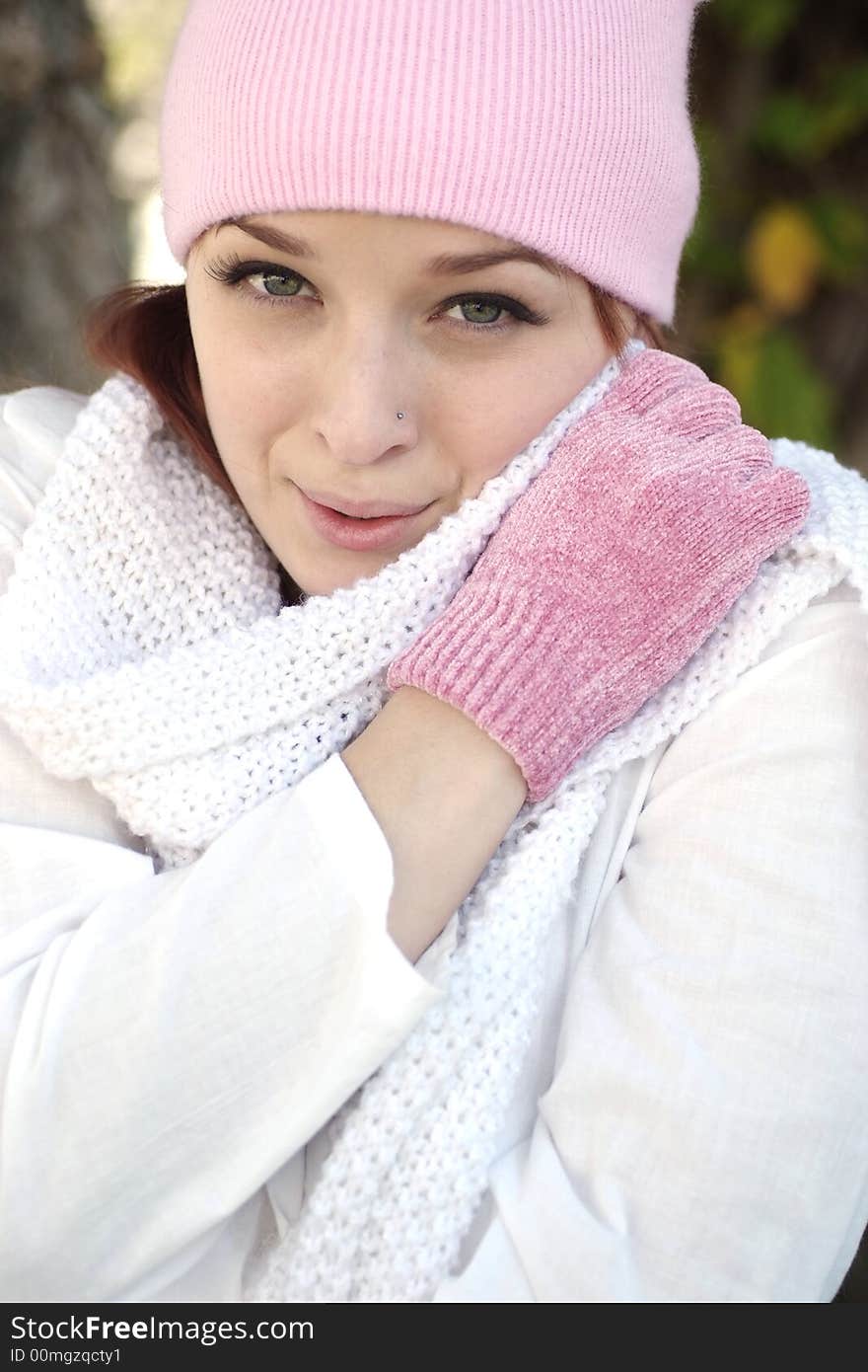 A beautiful woman with a red hair, white scarf, and pink bonnet and gloves. A beautiful woman with a red hair, white scarf, and pink bonnet and gloves.