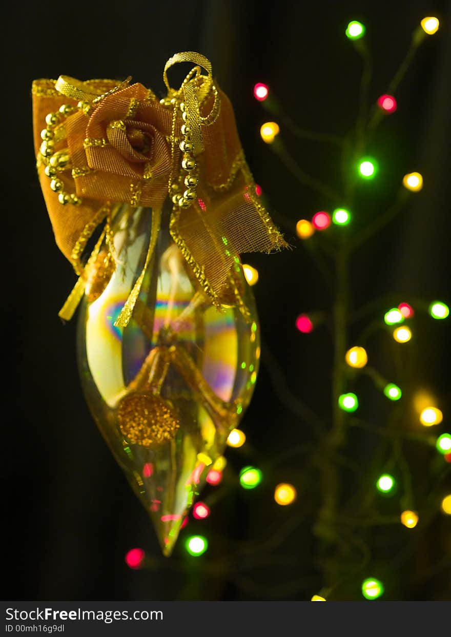 A refractive pointed ellipsoid ornamented with a fabric rose hung in mid air against a blur background of colored lights. A refractive pointed ellipsoid ornamented with a fabric rose hung in mid air against a blur background of colored lights.