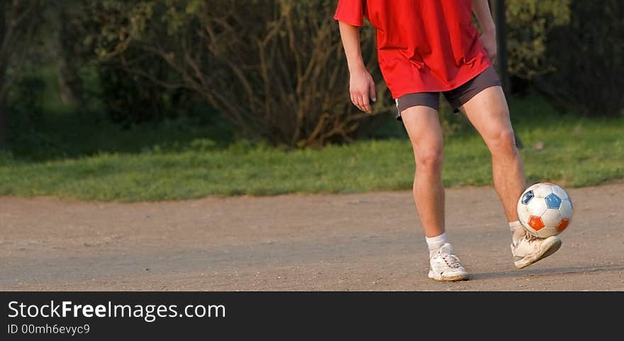 A football player's legs skilfully juggling with a ball. A lot of copy space on the left.