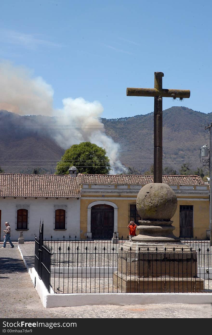 A tall statue with a crucifix in a square. A tall statue with a crucifix in a square