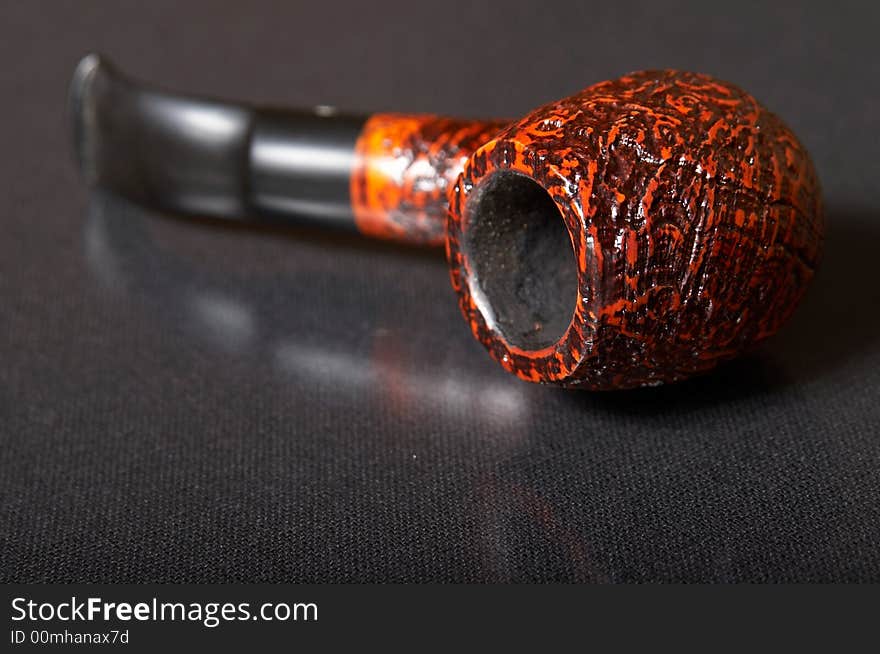 Red textured smoking pipe at black background