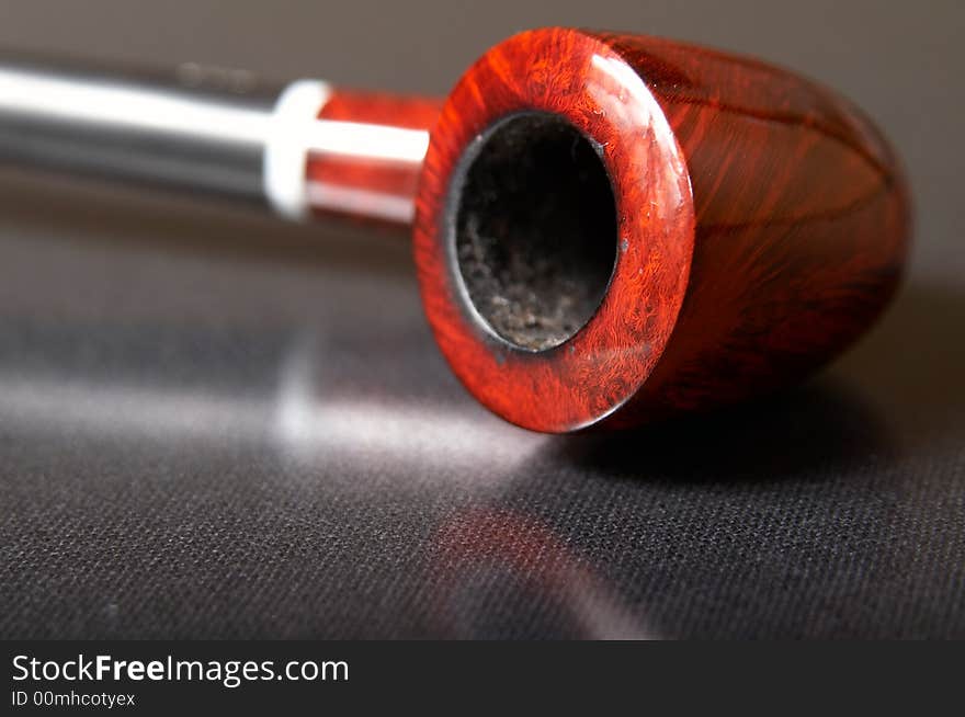 Red textured smoking pipe at black background